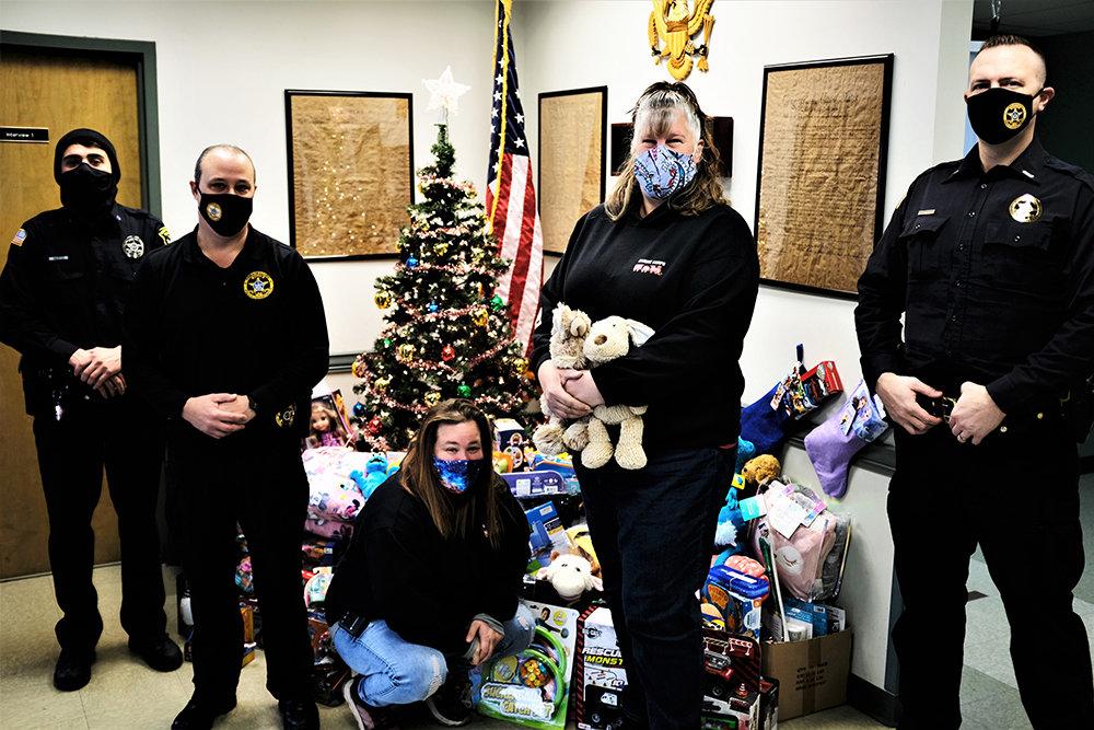 Tammy Haight (kneeling) and Karen Baxter collected toys that will be distributed to needy families for the holidays. Assisting is [L-R] Officer Nick Vazeos, Chief Jim Janso and Lt. Phil Roloson.